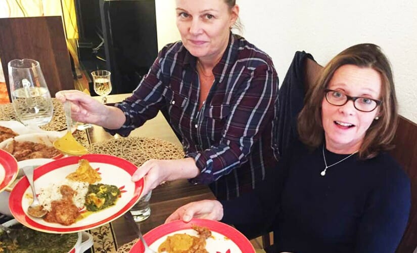 Two women with Indian food on a plate made at Indian cookery classes