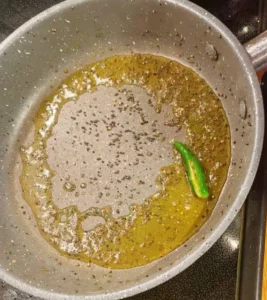 Mustard seeds and green chillies frying in a pan